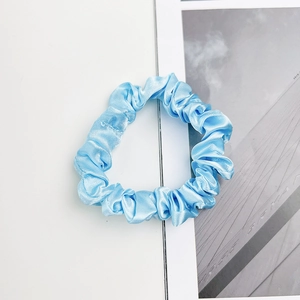 Gros plan d'un chouchou en satin bleu clair avec texture soyeuse et détails froissés