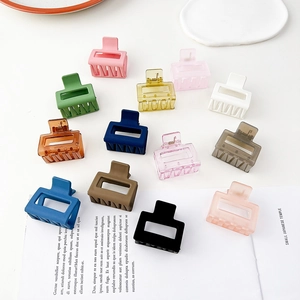 Dettaglio di mini mollette per capelli quadrate in vari colori opachi su una rivista