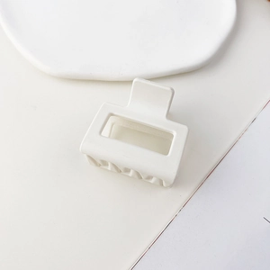 Macro della molletta quadrata bianca opaca con design geometrico vuoto su vassoio