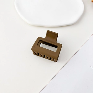 Macro di una molletta quadrata marrone opaco con design geometrico traforato