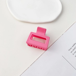 Dettaglio di una molletta quadrata rosa opaco posizionata su un vassoio bianco