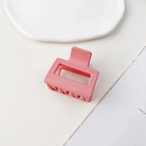 Dettaglio molletta per capelli quadrata rosa opaca su vassoio di ceramica bianca