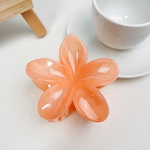 Détail de la pince à cheveux fleur orange en résine avec finition brillante sur blanc