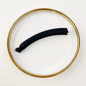 Close-up of matte black banana hair clip with non-slip teeth on a white decorative plate