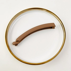 Detail view of brown matte banana hair clip with non-slip teeth on a white plate