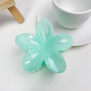 Détail d'une pince à cheveux fleur vert menthe sur fond blanc épuré et minimaliste