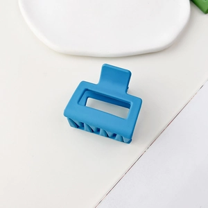 Macro di una molletta per capelli quadrata blu opaca su un vassoio in ceramica bianca