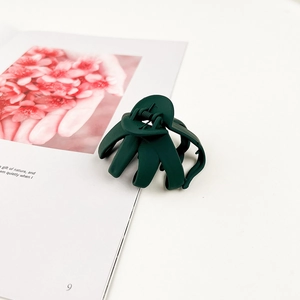 Dettaglio di un fermaglio per capelli verde scuro opaco con design a più denti