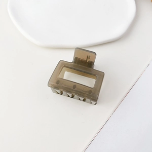 Dettaglio di un fermaglio per capelli quadrato grigio su un vassoio in ceramica