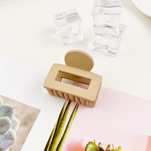 Dettaglio della pinza per capelli rettangolare beige opaco su rivista con cubetti di ghiaccio