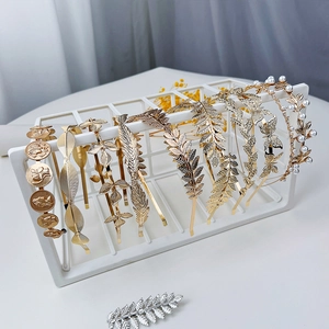 Dettaglio di eleganti cerchietti con foglie dorate e perle su supporto a rete bianco