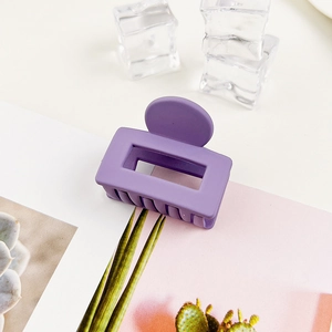 Dettaglio di un fermaglio per capelli rettangolare cavo viola opaco su uno sfondo estivo creativo