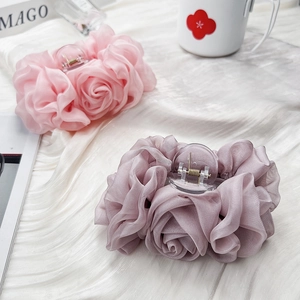 Detailaufnahme von Chiffon-Rosen-Haarklammern in Rosa und Mauve auf weißer Satinseide