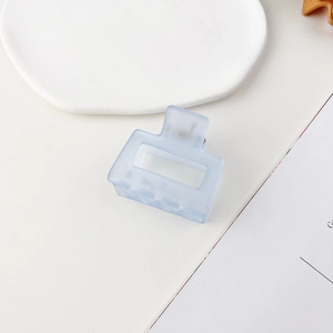 Dettaglio macro di una piccola molletta per capelli quadrata in plastica azzurra opaca