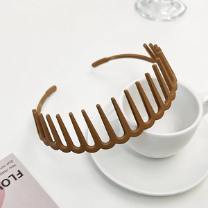 Close-up of a brown matte toothed headband resting on a stylish white ceramic coffee cup