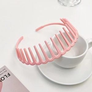 Detail of a pink matte non-slip headband with comb teeth leaning on a ceramic cup