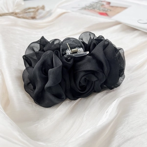 Nahaufnahme der großen schwarzen Organza-Rosen Haarklammer auf weichem Satin-Hintergrund
