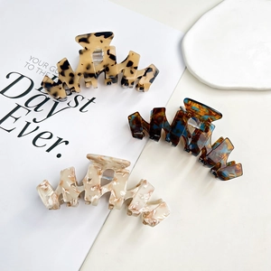 Detail view of large acetate hair claws in amber, blue marble, and beige shell patterns