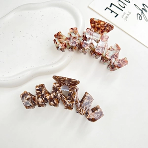 Macro detail of large acetate hair claw clip with brown marble pattern on ceramic tray