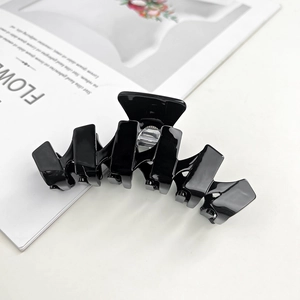 Detailed view of a large black acetate hair claw clip with a glossy finish on a magazine