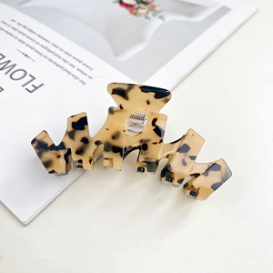 Detailed view of large tortoiseshell acetate hair claw clip on minimalist white background