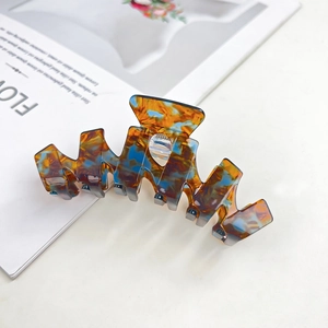 Detail of a large acetate shark hair claw featuring blue and amber marble textures