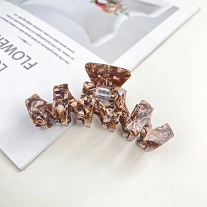 Detailed view of dark brown tortoiseshell acetate hair claw clip with wave design