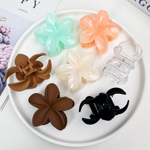 Vue détaillée de dessus des pinces à cheveux à fleurs mates en sept couleurs sur céramique