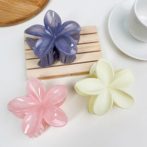 Vue détaillée des pinces à cheveux fleur de frangipanier mates en violet, rose et crème