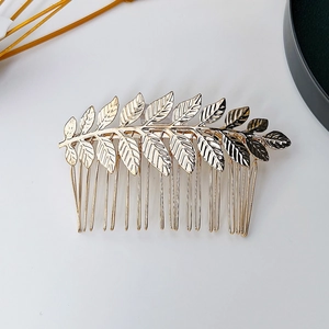 Dettaglio di un pettine per capelli in metallo dorato con foglie dal design vintage