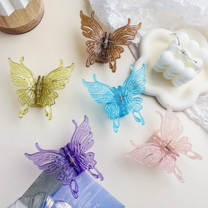 Cinq pinces à cheveux papillon en résine pastel disposées sur un fond esthétique beige