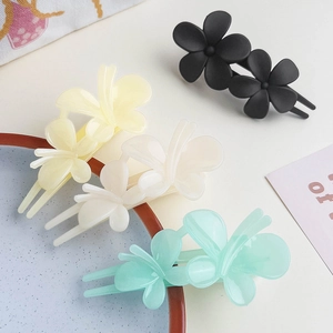 Detailed view of matte flower hair clips in black, yellow, white, and mint green colors