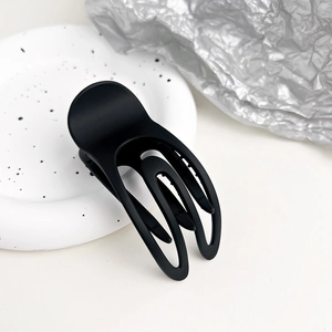 Dettaglio molletta per capelli cava nero opaco su piatto decorativo bianco elegante