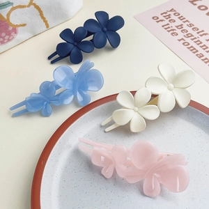 Close-up of four matte jelly-colored double flower hair clips on a decorative tray