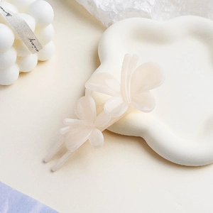 Detailed macro view of dual butterfly hair clip in frosted ivory acetate material