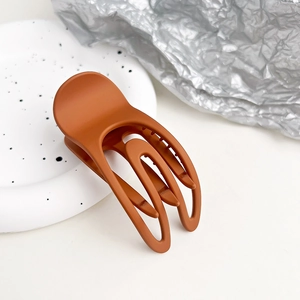 Dettaglio della pinza per capelli opaca color caramello a forma di U su piatto decorativo