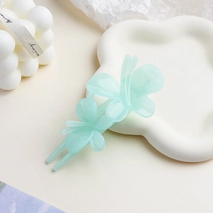 Detail of mint green double butterfly hair clip with frosted acrylic finish on white tray