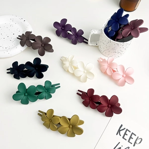 Close-up of matte double flower hair clips in various colors arranged on a white tray