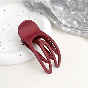 Dettaglio molletta per capelli opaca bordeaux su vassoio in ceramica elegante