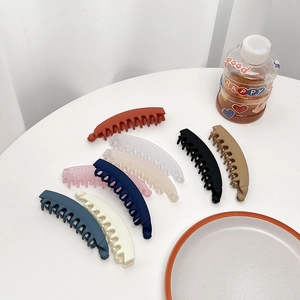 Dettaglio di fermagli a banana opachi in otto colori assortiti su un tavolo bianco