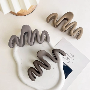 Macro shot of wavy matte hair claw clips in charcoal, mocha and khaki color set