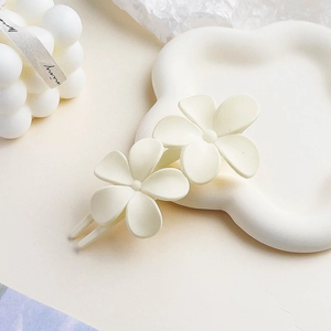 Detail of cream white matte flower hair clip on a minimalist aesthetic tray