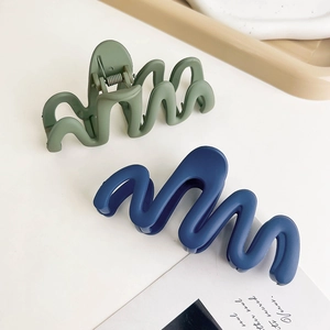 Detail view of army green and navy blue wave claw clips with matte finish on a tray