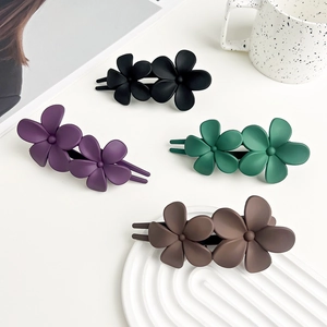 Detail view of four-color matte resin hair clips with double flower design on white background