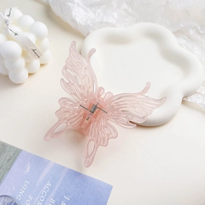 Détail d'une pince à cheveux papillon rose avec une texture en résine translucide mate