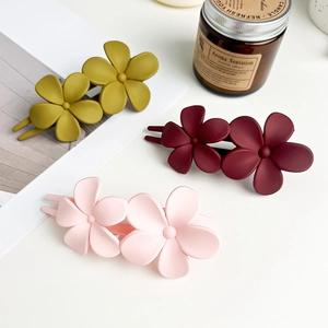 Frosted floral hair clips in olive green, burgundy, and light pink on a desk