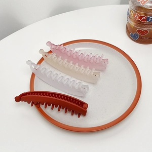 Dettaglio di quattro fermagli per capelli a banana opachi in diversi colori su un piatto