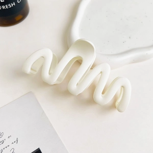 Detail showing white matte wave hair claw clip on a stylish decorative tray