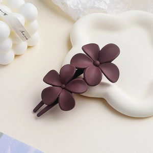 Close-up of matte burgundy double flower hair clip on a minimalist aesthetic tray