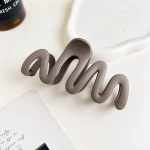 Detail view of wave-shaped matte hair claw clip in a neutral Morandi color palette